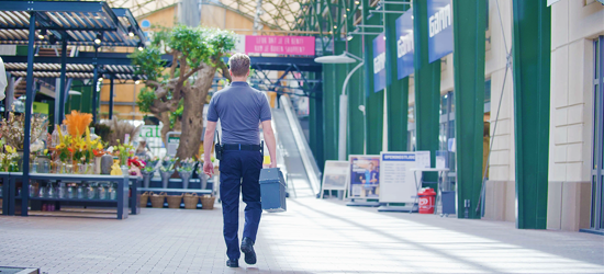 A man carrying a secure box through a shopping centre